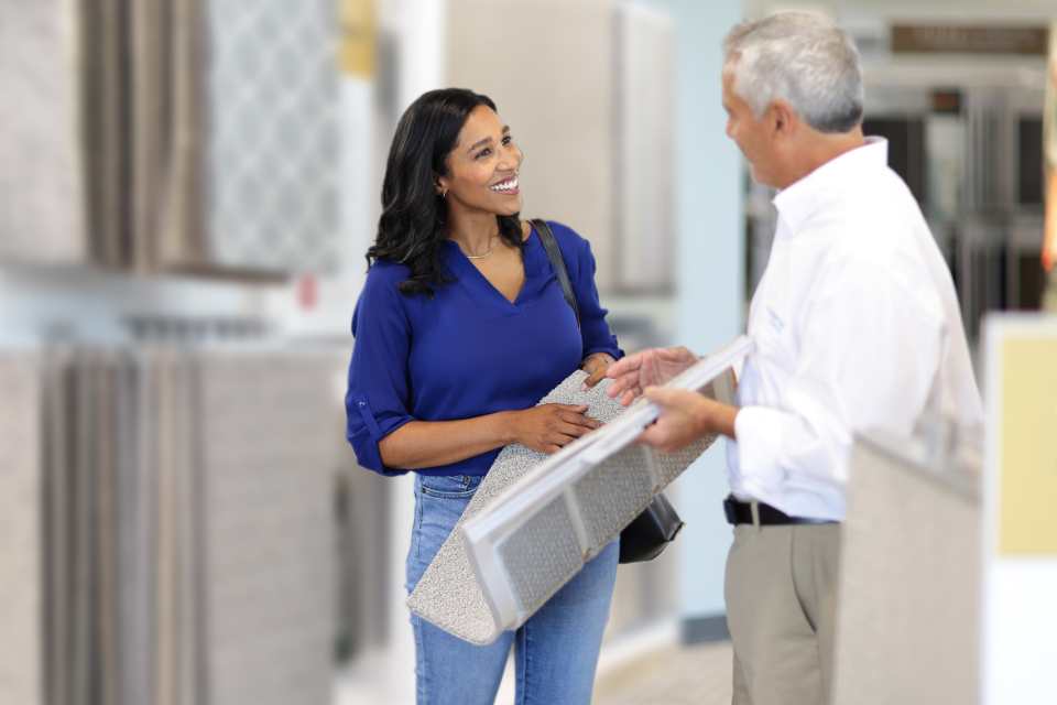 woman in showroom talking with sales associate about carpet samples